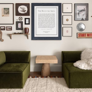 K&ouml;nnte beinhalten: Ein Innendesign-Szene mit einer Galeriewand mit gerahmter Kunst und einem Schild mit der Aufschrift "START WITH YES". Zwei olivgr&uuml;ne Samtsessel stehen sich gegen&uuml;ber, mit einem kleinen Holztisch dazwischen. Ein wei&szlig;er Teppich und ein dekoratives Geweih erg&auml;nzen die Einrichtung.