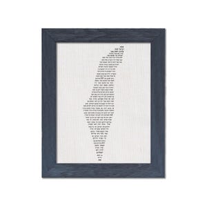 May include: Framed artwork featuring a white background with black text arranged in a vertical, stylized shape. The text appears to be in a foreign language. The frame is a dark blue-gray color, with a wood-like texture.