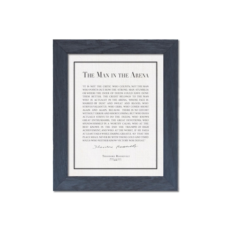 K&ouml;nnte beinhalten: Gerahmter Druck mit dunkelblauem Rahmen, der den Text "The Man in the Arena" von Theodore Roosevelt zeigt. Der Druck hat einen wei&szlig;en Hintergrund mit schwarzem Text. Das Zitat ist zentriert und enth&auml;lt Roosevelts Unterschrift.