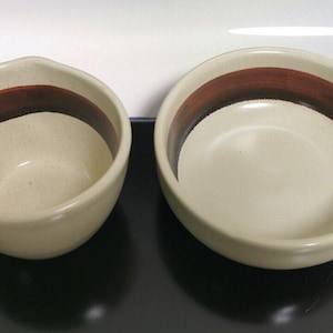 Puede incluir: Dos cuencos de cerámica con diseños de rayas marrones y blancas. Los cuencos tienen asas y son perfectos para servir sopa u otros platos.