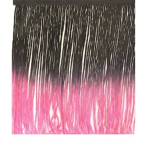 May include: Black and pink ombre fringe trim. The fringe is made of thin strands of yarn that are tied together at the top. The fringe is about 1 inch long.