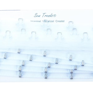 May include: White bra strap elastic with silver hooks and eyes. Sew Trendz, Sew Inspired, Realize! Create! is printed on the packaging.