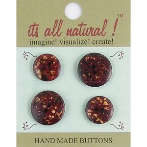 May include: Four round, dark brown buttons with mottled tan and cream speckles, arranged on a light green display card. The card features the text its all natural! imagine! visualize! create! and HAND MADE BUTTONS in dark brown lettering.
