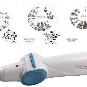 May include: A white hotfix applicator tool with a teal switch and a metal tip, accompanied by three circular white storage wheels containing assorted rhinestones. Each wheel is labeled HOTEE and BEST VALUE 300 PCS, featuring clear, black, and multicolored crystals.