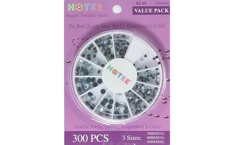 May include: A circular white plastic storage wheel containing assorted clear and black hot fix glass rhinestones. The packaging is purple with the text HOTEE, The Best Quality Glass Hot fix Rhinestones Crystals, 300 PCS, and 3 sizes: 3MM, 4MM, 5MM.