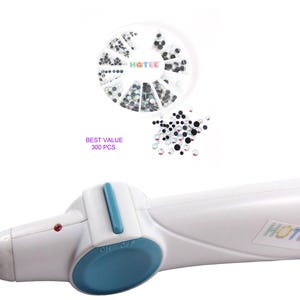 May include: A white handheld hotfix applicator tool with a blue switch and a metal tip, featuring a red indicator light. Included is a circular container with 300 pieces of assorted black and clear rhinestones, labeled BEST VALUE 300 PCS and HOTEE.