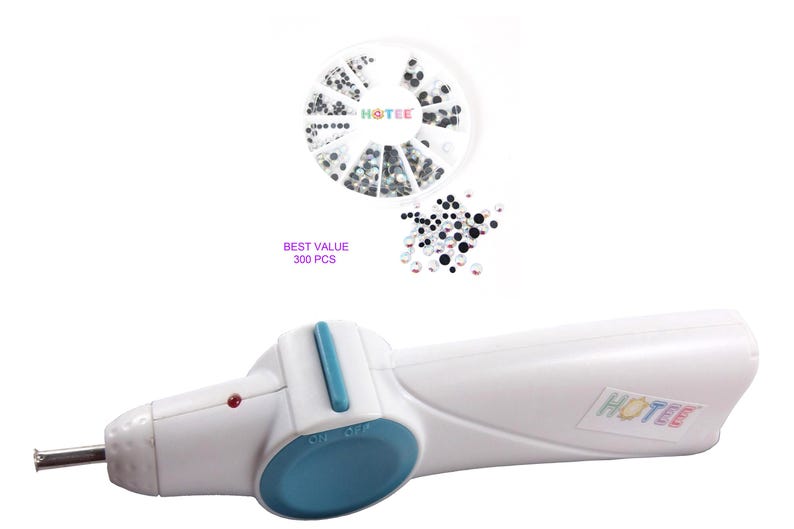 May include: A white handheld hotfix applicator tool with a blue switch and a metal tip, featuring a red indicator light. Included is a circular container with 300 pieces of assorted black and clear rhinestones, labeled BEST VALUE 300 PCS and HOTEE.