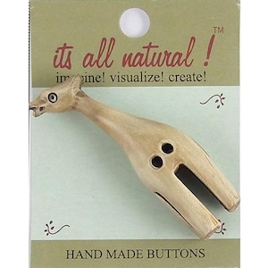 May include: A light brown wooden button shaped like a giraffe, featuring two holes for attachment. The button is mounted on a rectangular card with the text its all natural! imagine! visualize! create! and HAND MADE BUTTONS printed on it.