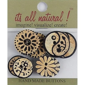 May include: A set of round buttons on a card labelled its all natural! imagine! visualize! create! and HAND MADE BUTTONS. The buttons feature black and tan patterns including a yin-yang symbol, a flower, and a sunburst design with carved details.