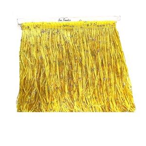 May include: Yellow fringe trim with iridescent sequins. The trim is attached to a clear plastic header with the text "Sew Trends®" printed on it. The fringe is made of long, thin strands.