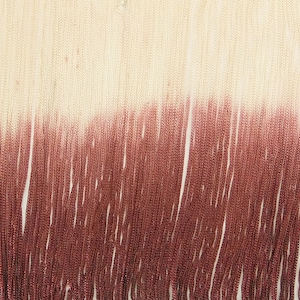 May include: A close-up of a fringe trim with a gradient of color from white to burgundy.