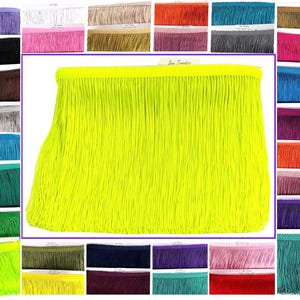 May include: A vibrant display of fringe trim in various colors, including neon yellow, pink, teal, and purple. The main focus is a large section of bright yellow fringe, with smaller samples of different colors surrounding it. The trim is likely used for crafting or apparel.