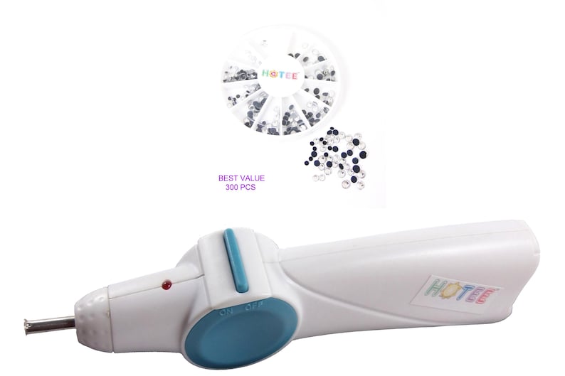 May include: A white handheld hotfix applicator tool with a blue button and a metal tip, accompanied by a circular plastic container holding clear and black rhinestones, with the text HOTEE and BEST VALUE 300 PCS visible on the items.