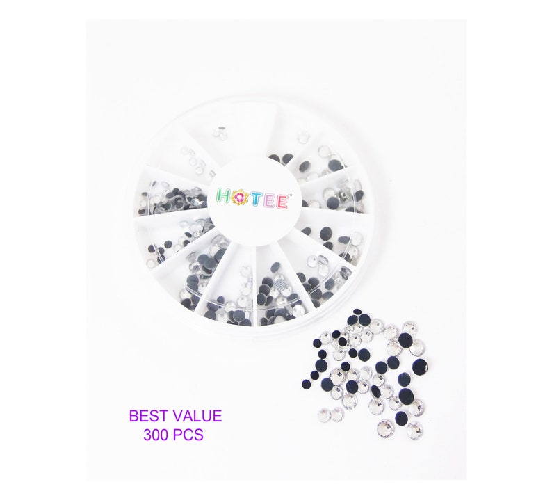 May include: A white circular plastic storage container with twelve divided compartments containing small clear round rhinestones. The center of the lid features the text HOTEE. A pile of loose clear rhinestones sits nearby with the text BEST VALUE 300 PCS.