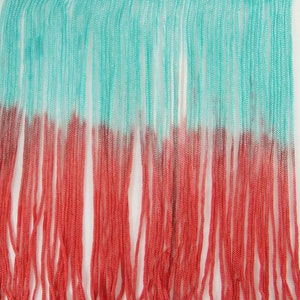 May include: A turquoise and coral ombre fringe trim with a woven top edge. The fringe is made of thin strands of yarn.