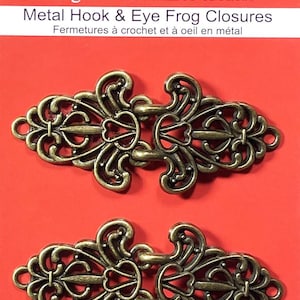 May include: Two ornate metal hook and eye closures in an antique gold finish. The closures are designed with intricate floral patterns and are perfect for adding a touch of elegance to any sewing project.