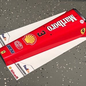 May include: A red and white Formula One car nose cone with the Marlboro logo, Shell logo, FedEx logo, and the number 3. The car is also sponsored by Bridgestone, Fiat, and Magneti Marelli.