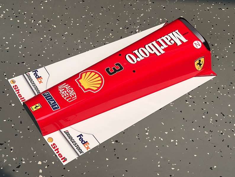 May include: A red and white Formula One car nose cone with the Marlboro logo, Shell logo, FedEx logo, and the number 3. The car is also sponsored by Bridgestone, Fiat, and Magneti Marelli.