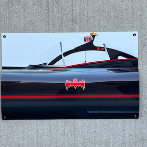 K&ouml;nnte beinhalten: Ein schwarzer und roter Batmobile aus der Batman-Fernsehserie der 1960er Jahre. Das Auto hat ein rotes Fledermaussymbol an der Seite und einen roten Streifen entlang der Unterseite.