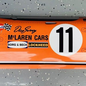 May include: Orange and white race car tail section with the number 11, the words "McLaren Cars", "Borg & Beck", and "Lockheed", and the Gulf logo.