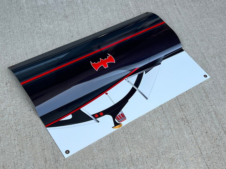 K&ouml;nnte beinhalten: Ein schwarz-wei&szlig;es Banner mit einem roten Fledermaus-Symbol und einem roten Streifen. Das Banner ist gebogen und hat einen wei&szlig;en Hintergrund mit einem schwarz-wei&szlig;en Bild eines Autos.