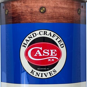 May include: A blue and white sign with a red circle containing the text "Case XX" and the words "Hand-Crafted Knives" around the circle. The sign has a woodgrain border.