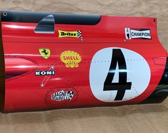 May include: A red and black race car side panel with a white circle containing the number "4" in black. The panel has various sponsor logos including "Shell", "Champion", "Koni", "Magneti Marelli", and "Britax".