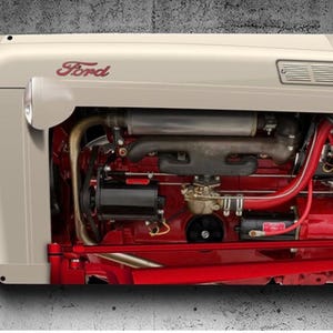 May include: Close-up of a vintage Ford tractor engine. The tractor hood is cream-coloured with the Ford logo in red script. The engine components are red and black, with silver pipes and a black air filter.