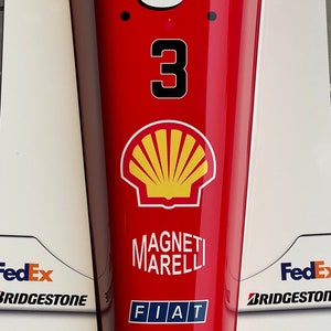 May include: A red race car with the number 3 on the side. The car has sponsors including Shell, FedEx, Bridgestone, and Fiat. The car is a Ferrari.