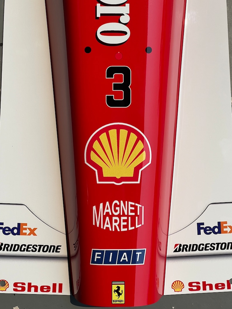 May include: A red race car with the number 3 on the side. The car has sponsors including Shell, FedEx, Bridgestone, and Fiat. The car is a Ferrari.