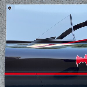 K&ouml;nnte beinhalten: Ein schwarzer und roter Batmobil mit einem klaren Heckfenster. Das Auto hat einen roten Streifen an der Seite und ein Fledermauslogo auf der R&uuml;ckseite.