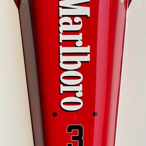 May include: A red race car with the word "Marlboro" written in white letters on the side. The car has a black number "3" on the side and a black "N" in a white circle on the top.