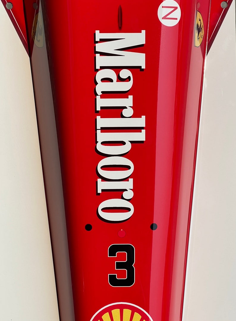 May include: A red race car with the word "Marlboro" written in white letters on the side. The car has a black number "3" on the side and a black "N" in a white circle on the top.