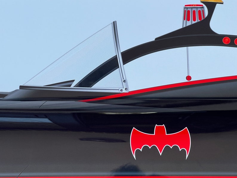 K&ouml;nnte beinhalten: Ein schwarzer und roter Batmobil mit einer klaren Windschutzscheibe und einem roten Fledermaus-Symbol an der Seite.