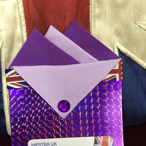 May include: A purple iridescent envelope with a white label that reads "HIPSTER UK 38 WEST STREET DUNSTABLE BEDS LU6 1TA" and a small Union Jack flag sticker. The envelope has a purple rhinestone in the center.