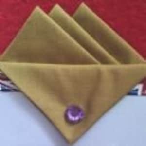 May include: Three folded olive green fabric napkins with a purple button on the top napkin.
