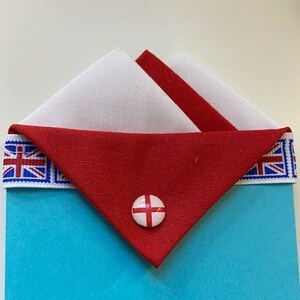 May include: A blue card with a red, white, and blue fabric envelope with a small red, white, and blue button in the center. The fabric envelope has a white border with a red, white, and blue pattern.
