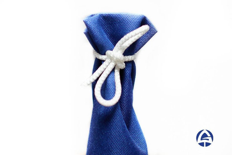 Puede incluir: Una bolsa de tela azul real con un tejido texturizado, cerrada en la parte superior con un cord&oacute;n trenzado blanco atado en un nudo simple. La bolsa est&aacute; orientada verticalmente sobre un fondo blanco liso y presenta un logo azul y blanco.
