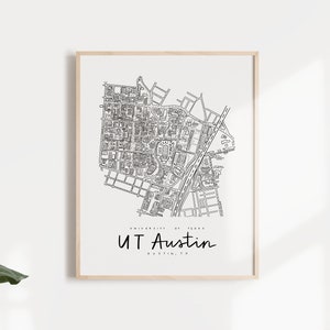May include: A black and white line art print of the University of Texas at Austin campus map. The print is framed in a light wood frame and has the text "UT Austin" below the map.