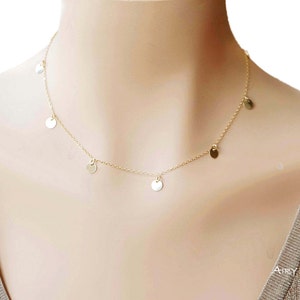 May include: A gold chain necklace with small round gold charms hanging from it.