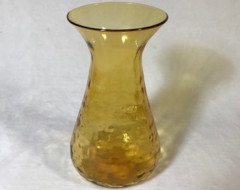 May include: A clear amber glass vase with a textured surface. The vase has a wide mouth and a narrow neck.