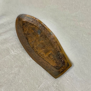 May include: An oval-shaped, brass tray with an intricate, embossed design. The tray has a warm, golden color and a slightly worn finish.