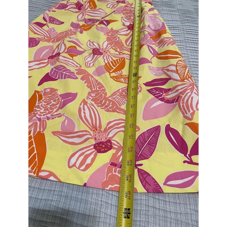 May include: A yellow skirt with a vibrant floral pattern in shades of pink, orange, and white. The skirt is measured with a tape measure, showing a length of approximately 36 inches.
