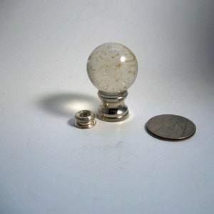 May include: A clear glass finial with a silver base and a silver finial ring. The finial is about the size of a UK 20 pence coin.