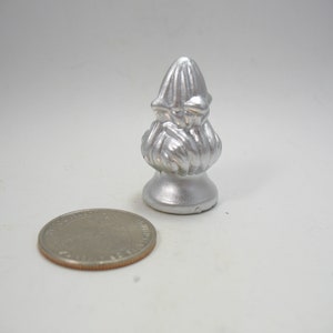 May include: Silver metal finial with a decorative, ornate design. The finial is about the size of a US quarter.