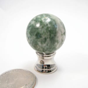 May include: A green and white agate sphere finial with a silver base. The finial is about the size of a US quarter.