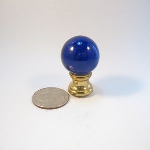 May include: A blue glass finial with a brass base. The finial is about the size of a US quarter.