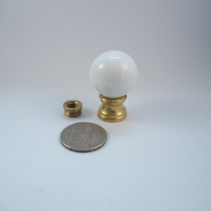 May include: White ceramic lamp finial with a brass base. The finial is about the size of a US quarter.