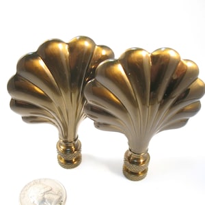 Peut inclure: Deux embouts de lampe en métal couleur or en forme de coquillages. Les embouts ont une finition brillante et polie.