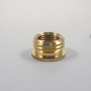 May include: A gold-colored metal adapter with a threaded opening and a flat base.